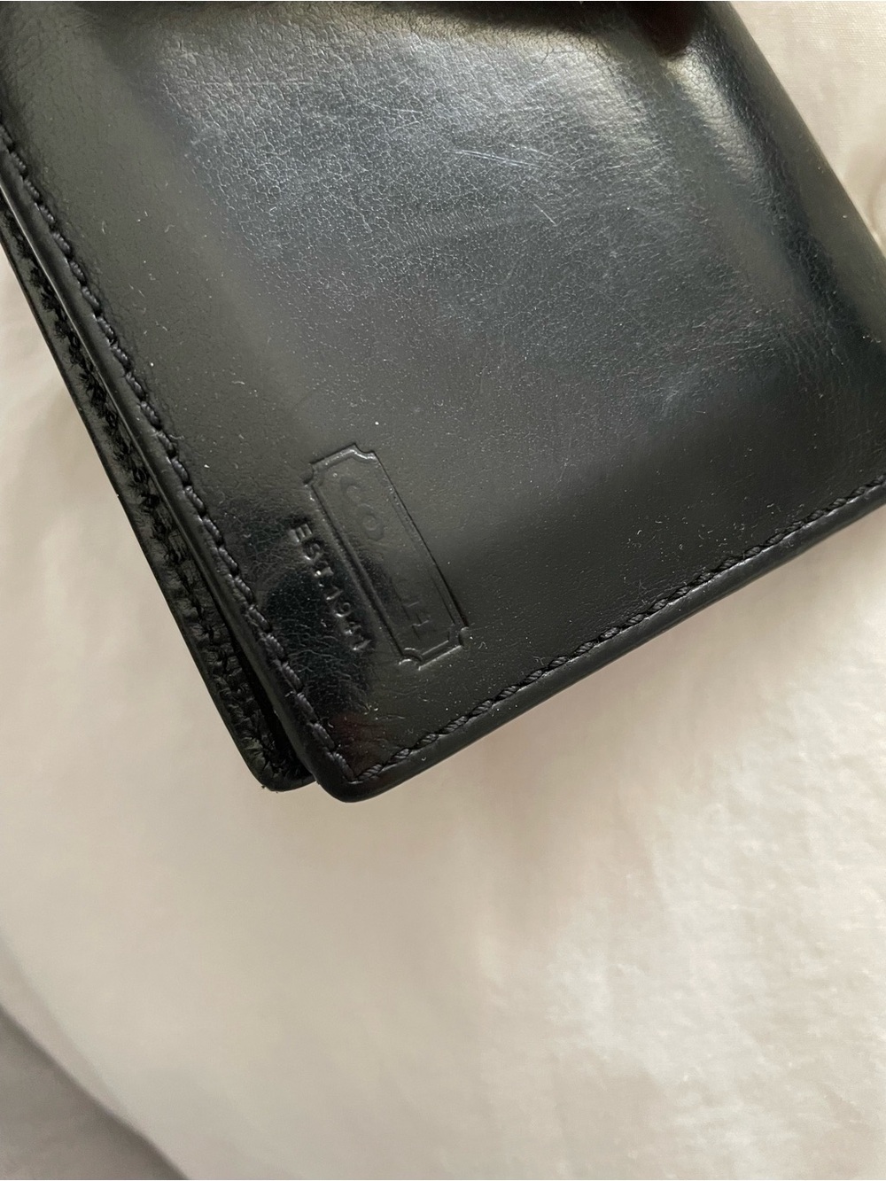 Coach compact bifold wallet featuring an embossed "EST. 1941"